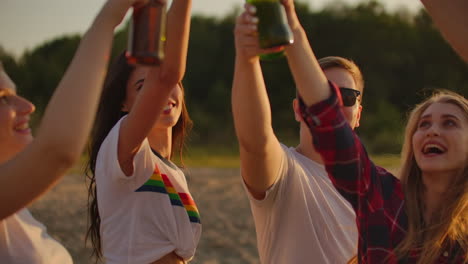 Young-people-celebrate-the-end-of-the-semester-with-beer-and-pop-music-on-the-beach-with-their-friends.-They-clink-and-drink-beer-on-the-open-air-party.